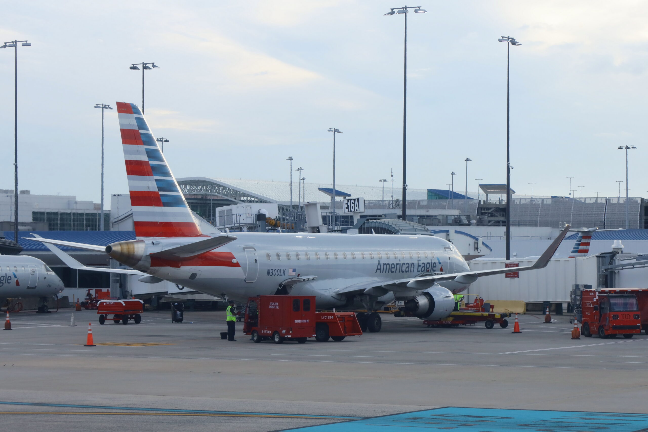 American Airlines jet parked at the gate with ground support vehicles on the tarmac