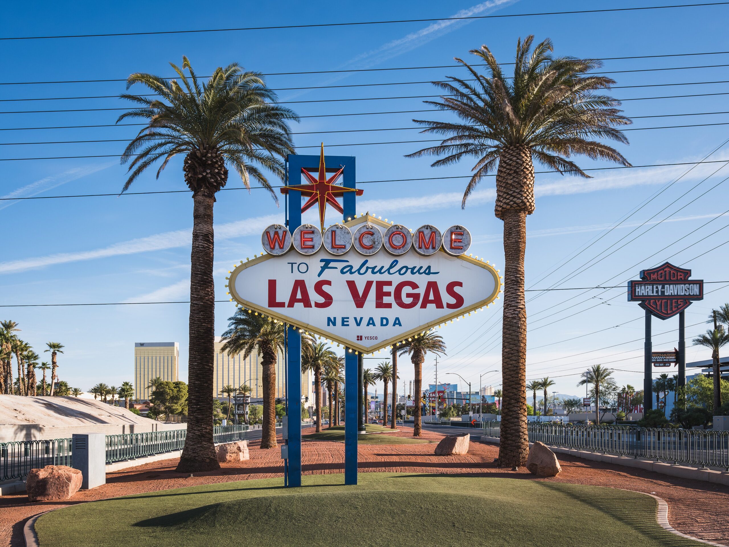 Welcome sign for Las Vegas with palm trees and a clear blue sky behind it.